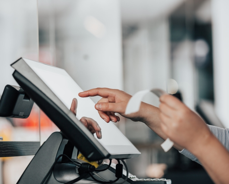 Une jeune vendeuse utilise un système de caisses enregistreuses ready4pos pour encaisser une table au restaurant